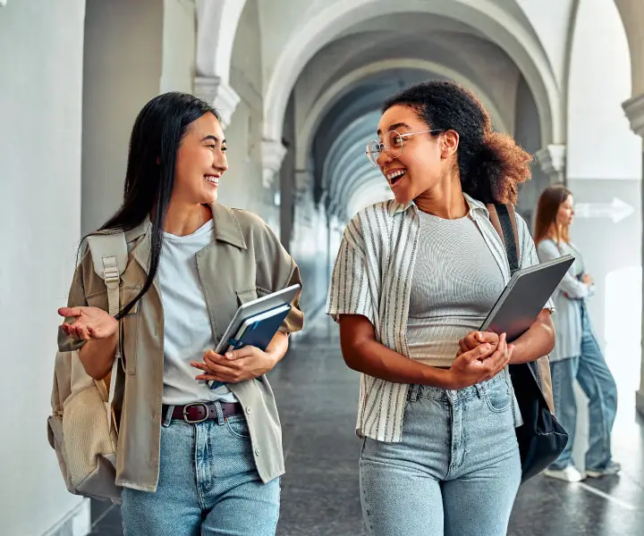 Two women walking and talking outdoors on a campus.