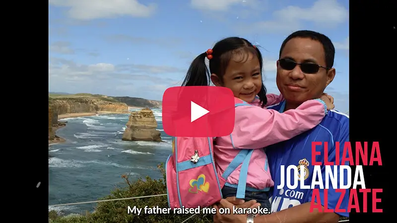 Scholarship winner video thumbnail for Eliana Jolanda Alzate holding a child on a coastal clifftop, captioned 'My father raised me on karaoke.'