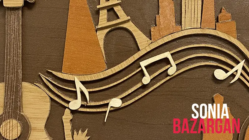 Scholarship winner Sonia Bazargan, beside a carved wooden artwork of the Eiffel Tower with musical notes.