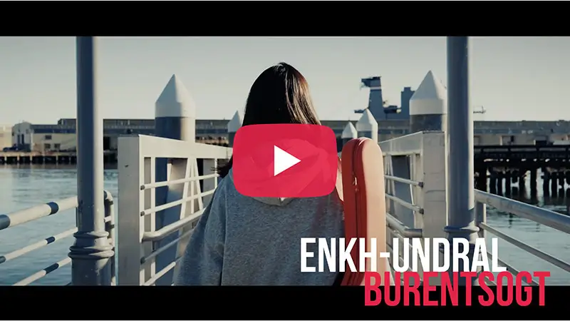 Scholarship winner video thumbnail for Enkh-Undral Burentsogt at a waterfront railing overlooking a city skyline.