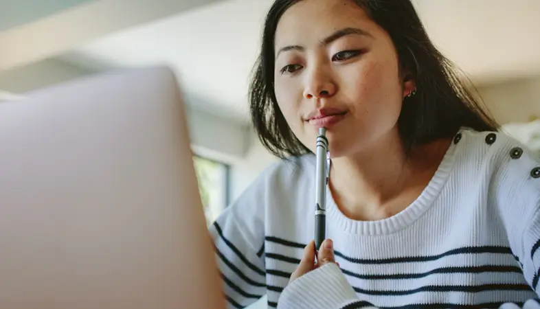 Một cô gái trẻ đang nhìn vào máy tính xách tay trong một buổi khám bệnh từ xa qua video.